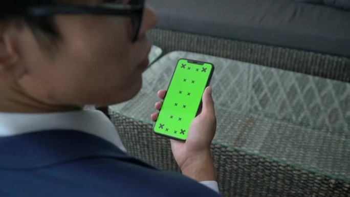 商人在绿屏手持智能手机上寻找智能手机