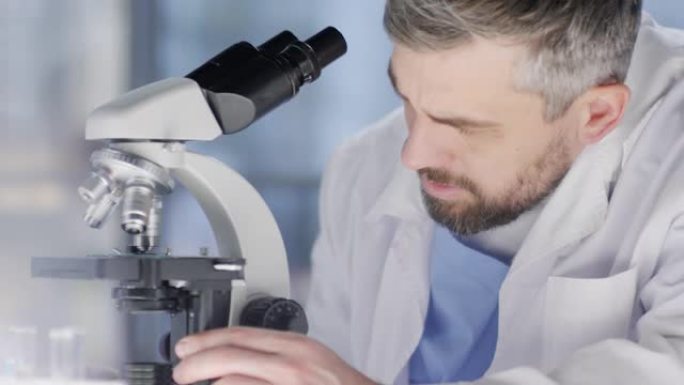 男性高加索研究人员凝视着显微镜