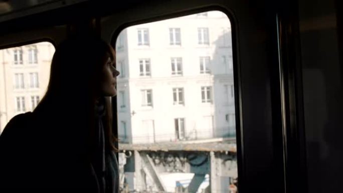 年轻快乐美丽的旅游女人在巴黎的地铁列车上透过窗户慢动作看着城市建筑。