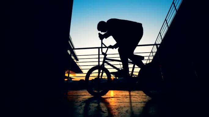 骑自行车的人在日落背景上跳上一个轮子，慢动作。