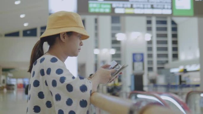 亚洲旅游妇女在机场候机楼等候和使用智能手机。