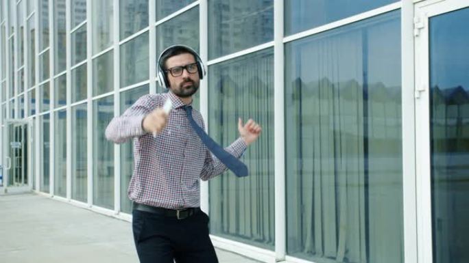 快乐的企业家戴着耳机在户外跳舞的慢动作