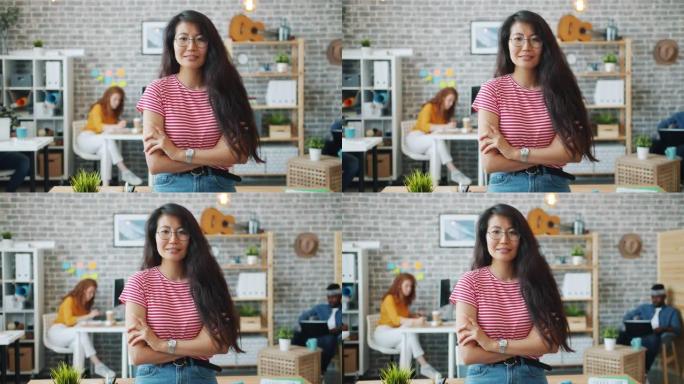 迷人的亚洲女士站在办公室室内双臂交叉的肖像