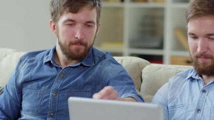 男性双胞胎用笔记本电脑浏览互联网