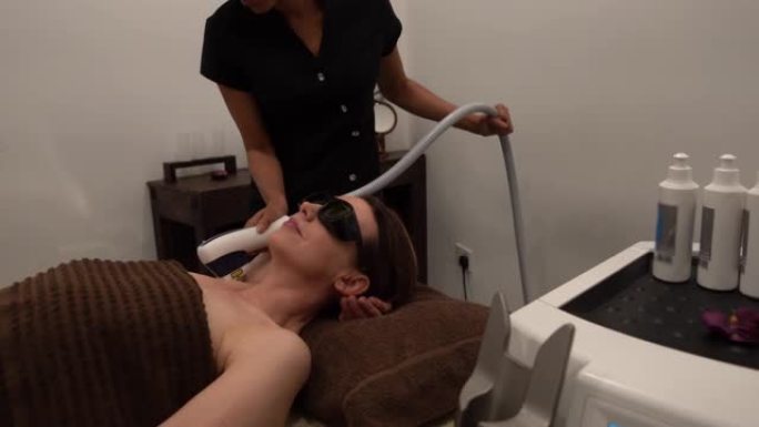 黑人美容师在水疗中心用激光对腋下的女性顾客进行激光治疗