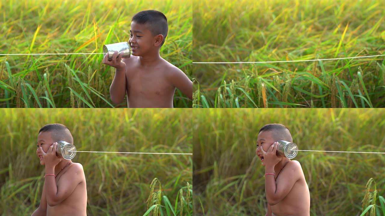 快乐的亚洲男孩玩锡罐电话。