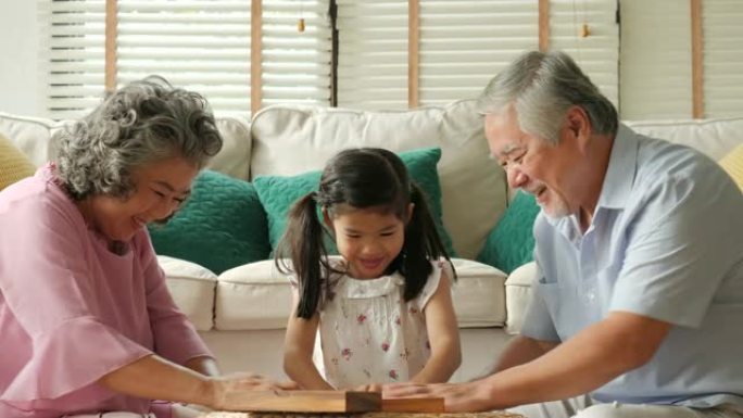 亚洲高级夫妇在家里和一个小女孩一起玩。高级生活方式家庭概念。