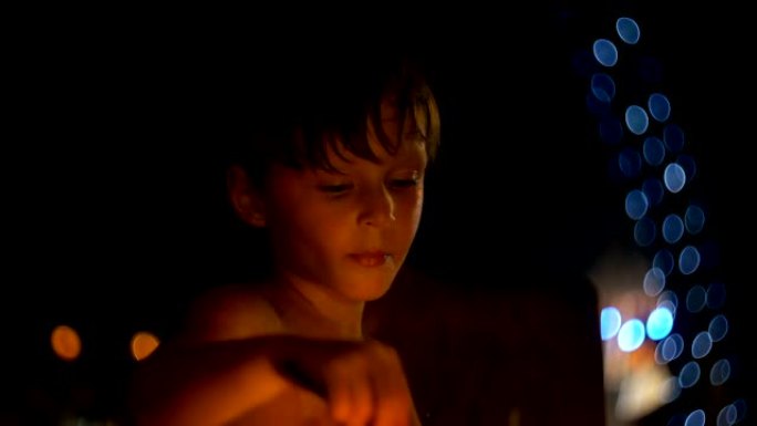 快乐放松的欧洲小男孩在大气的晚间海滩酒吧用大勺子吃甜点，那里有波克灯。