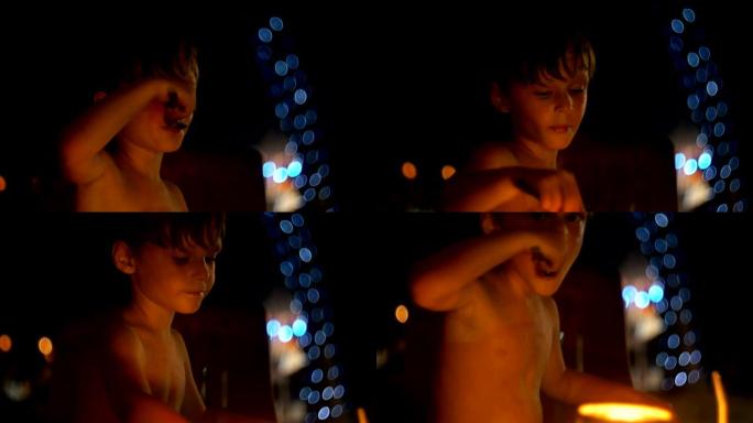 快乐放松的欧洲小男孩在大气的晚间海滩酒吧用大勺子吃甜点，那里有波克灯。