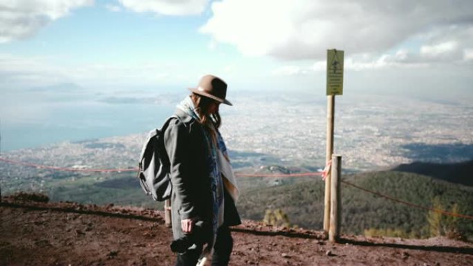 年轻美丽的女游客的侧视图，背着背包从维苏威火山徒步旅行，欣赏那不勒斯的景色。