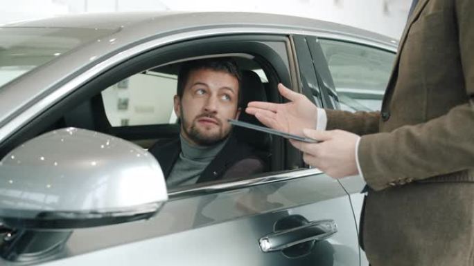 好看的男人买家与坐在车里触摸闪亮汽车的销售经理交谈