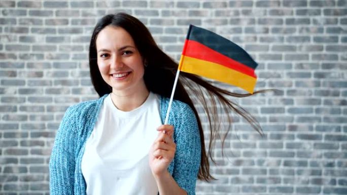 在砖墙背景上举着德国国旗的美女肖像