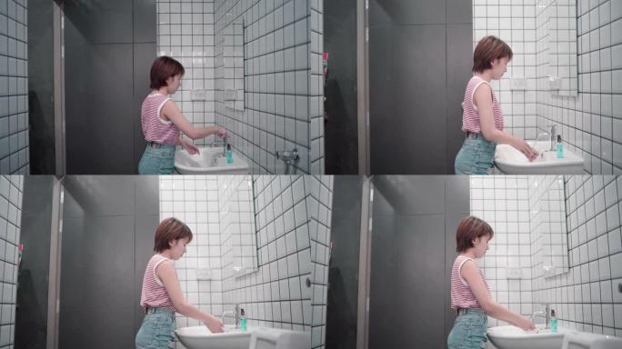 亚洲妇女在厕所，洗手间里用消毒肥皂仔细洗手。