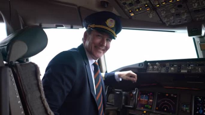 一架商用飞机的英俊飞行员坐在驾驶舱前看着相机微笑着挥手