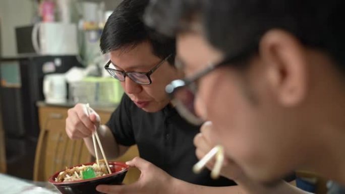两名男子用筷子吃日本便当盒