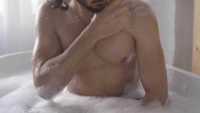 年轻有魅力的男人用海绵洗澡