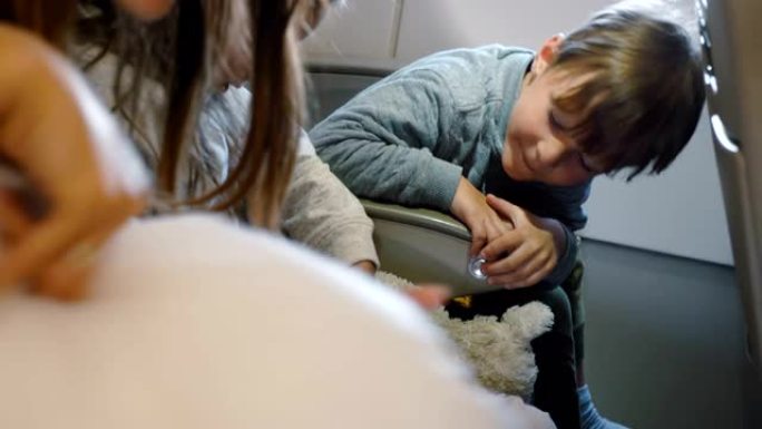 和家人一起去度假的飞机飞行中，快乐可爱的小男孩和女孩系好安全带的侧视图。