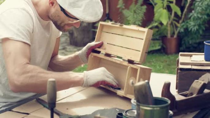 花园DIY。男人打磨木制家具。
