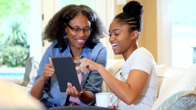 年轻女子和她的妈妈在数字平板电脑上看照片
