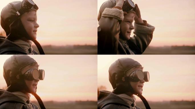 身着旧飞行员服装的快乐小男孩在日落场慢动作中戴着老式航空眼镜的特写镜头。