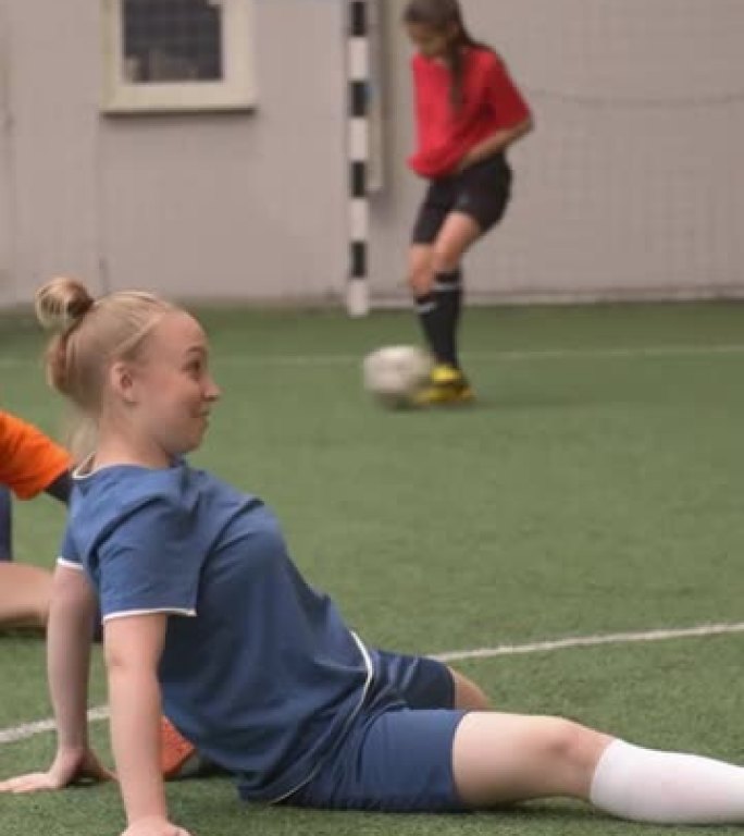 足球女孩在室内运动场上的伸展和训练