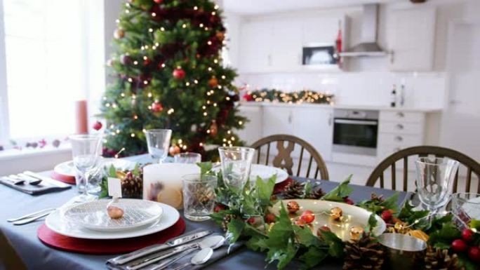 一张节日圣诞餐桌，盘子上摆着摆设的小玩意儿名片夹，还有绿色和红色的季节性装饰品，高景