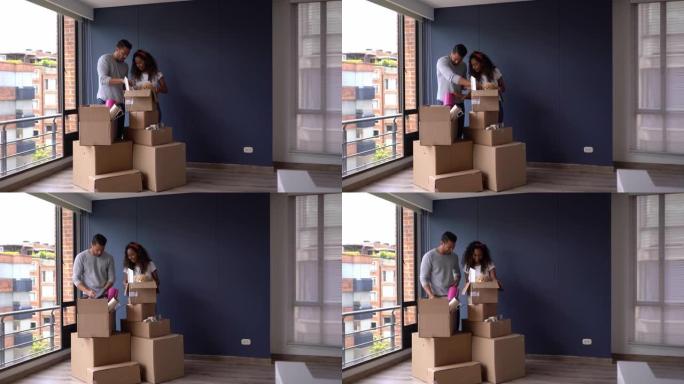 多样化的年轻夫妇准备在他们的新公寓里打开箱子，拥抱和微笑