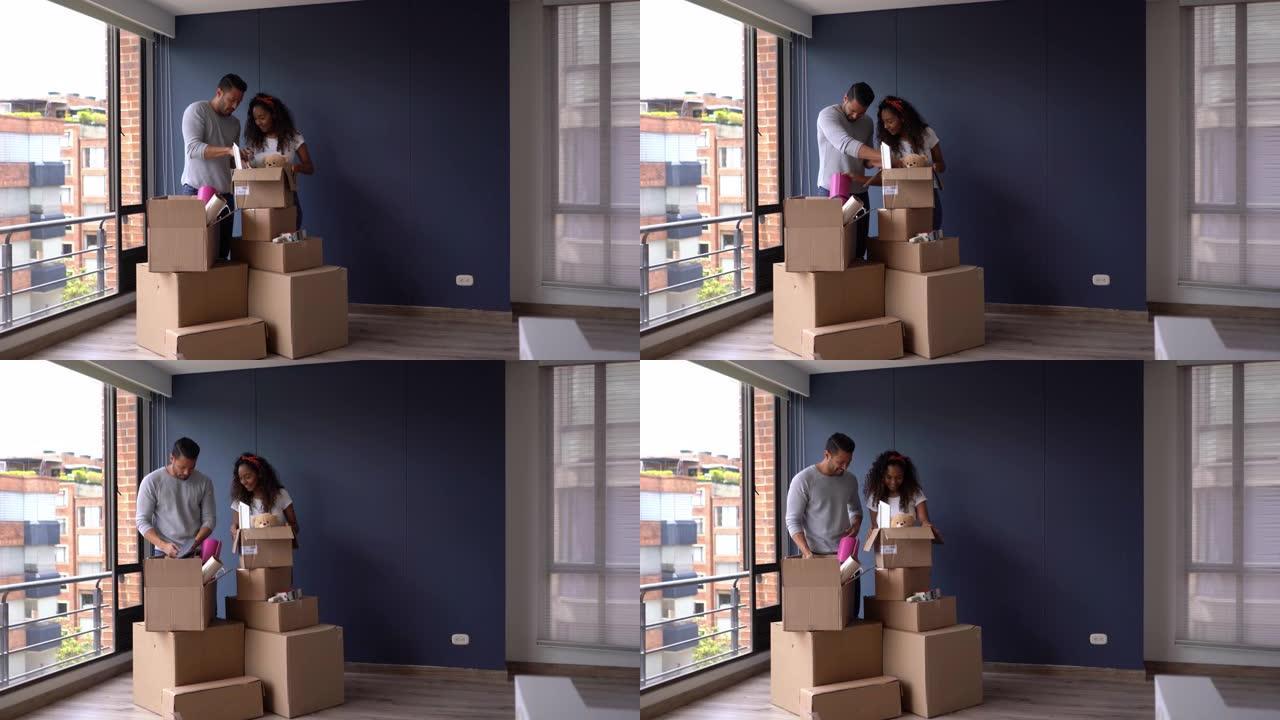 多样化的年轻夫妇准备在他们的新公寓里打开箱子，拥抱和微笑