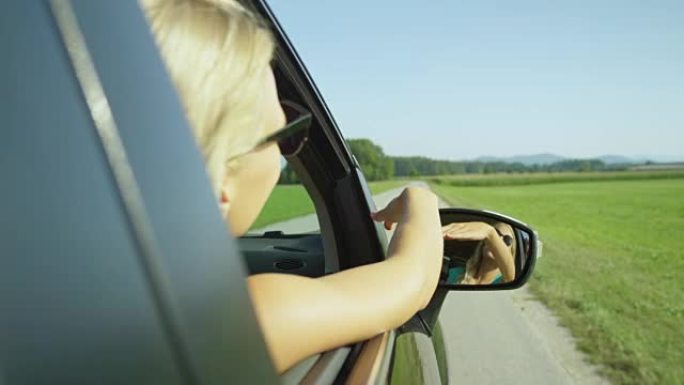 慢动作: 无忧无虑的高加索女孩在开车时在空中挥舞着手臂