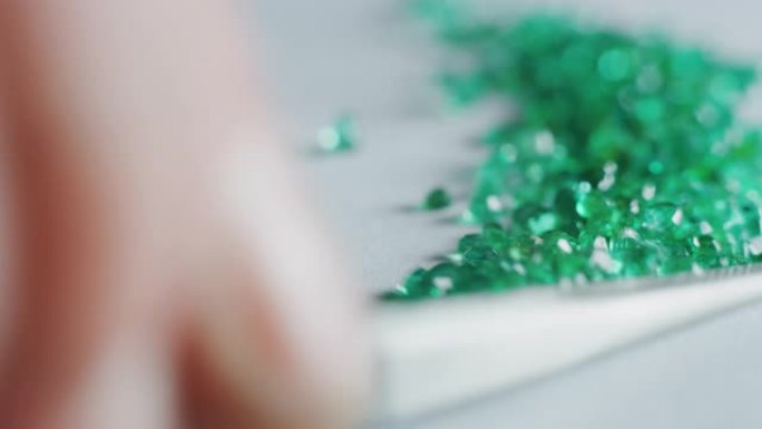 经验丰富的金匠的慢动作宏对高质量的绿色钻石进行分类，选择它们在车间制作珍贵的珠宝。