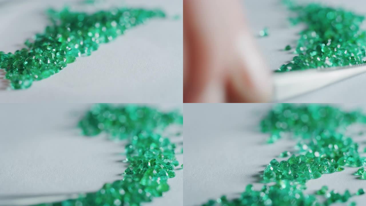 经验丰富的金匠的慢动作宏对高质量的绿色钻石进行分类，选择它们在车间制作珍贵的珠宝。