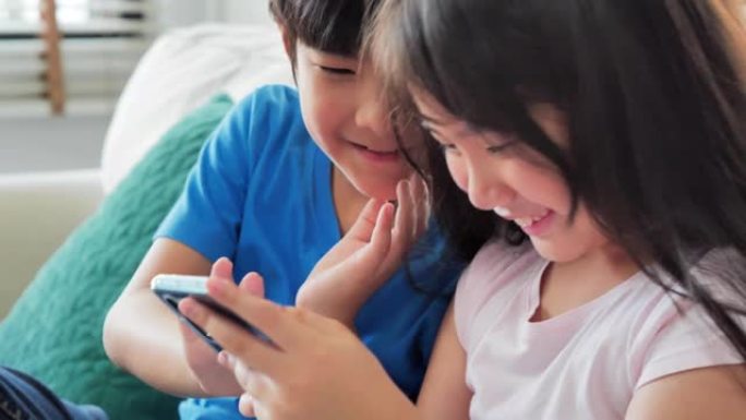 快乐的孩子坐在沙发上，在智能手机上打字。让孩子玩智能手机快乐有趣。早期教育d learning.ed