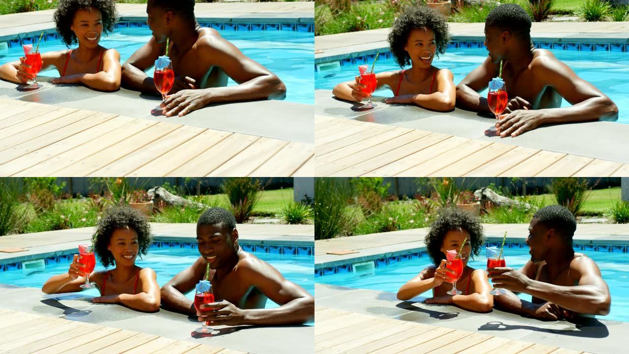 4k度假村游泳池里年轻黑人夫妇敬酒杯鸡尾酒的前视图