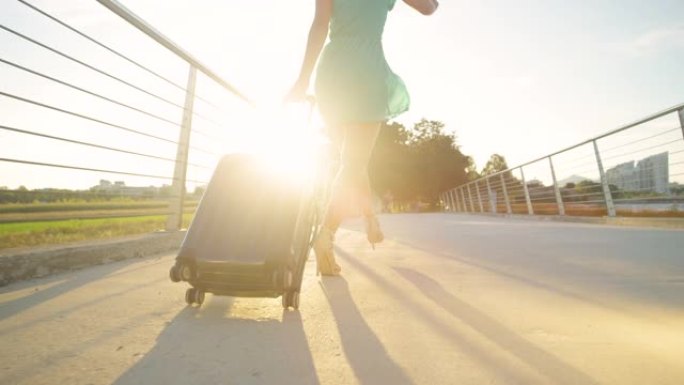 低角度: 穿着高跟鞋的年轻女子在日落时分步行到机场时跳