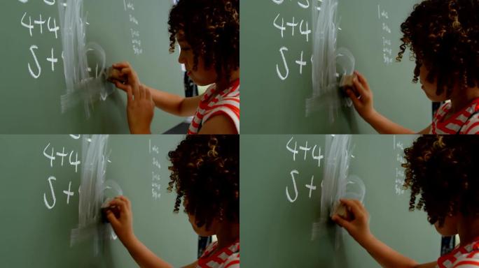 4k学校教室里混血女学生清洁绿色黑板的侧视图
