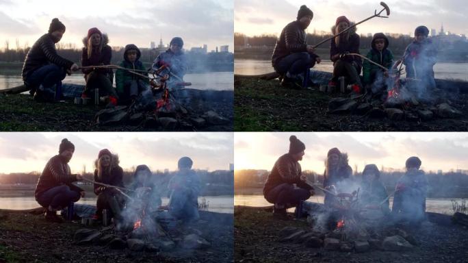 篝火里的家庭烤香肠。冬季乐趣。城市中的河边