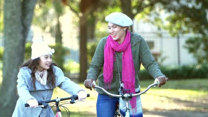 西班牙裔母亲和女儿在公园骑自行车