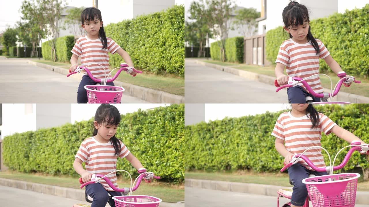 亚洲小女孩在花园里骑自行车