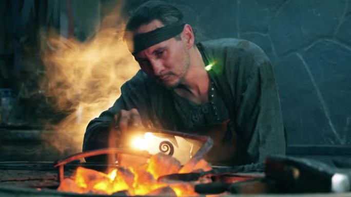 男铁匠在检查煤时使用扑克。