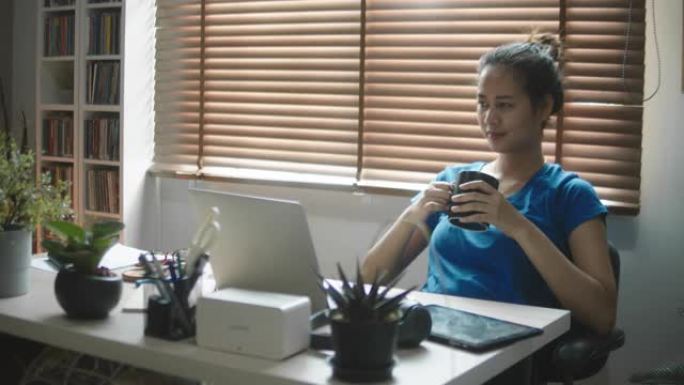 亚洲女性在家里使用笔记本电脑而苦苦挣扎。