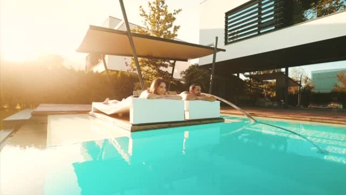 年轻夫妇在游泳池边晒日光浴。