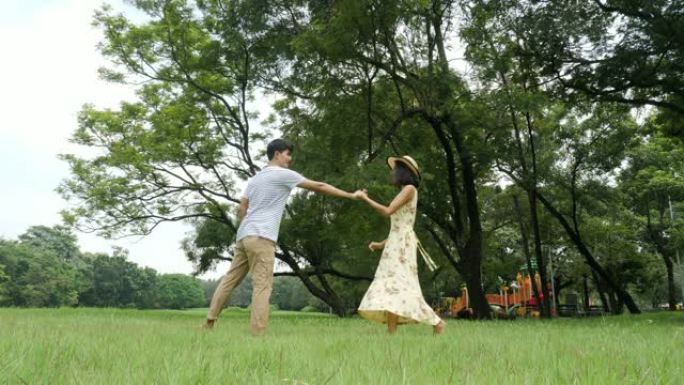 浪漫的亚洲夫妇带着快乐的情感在花园里跳舞。人们有生活方式，放松情感的概念。