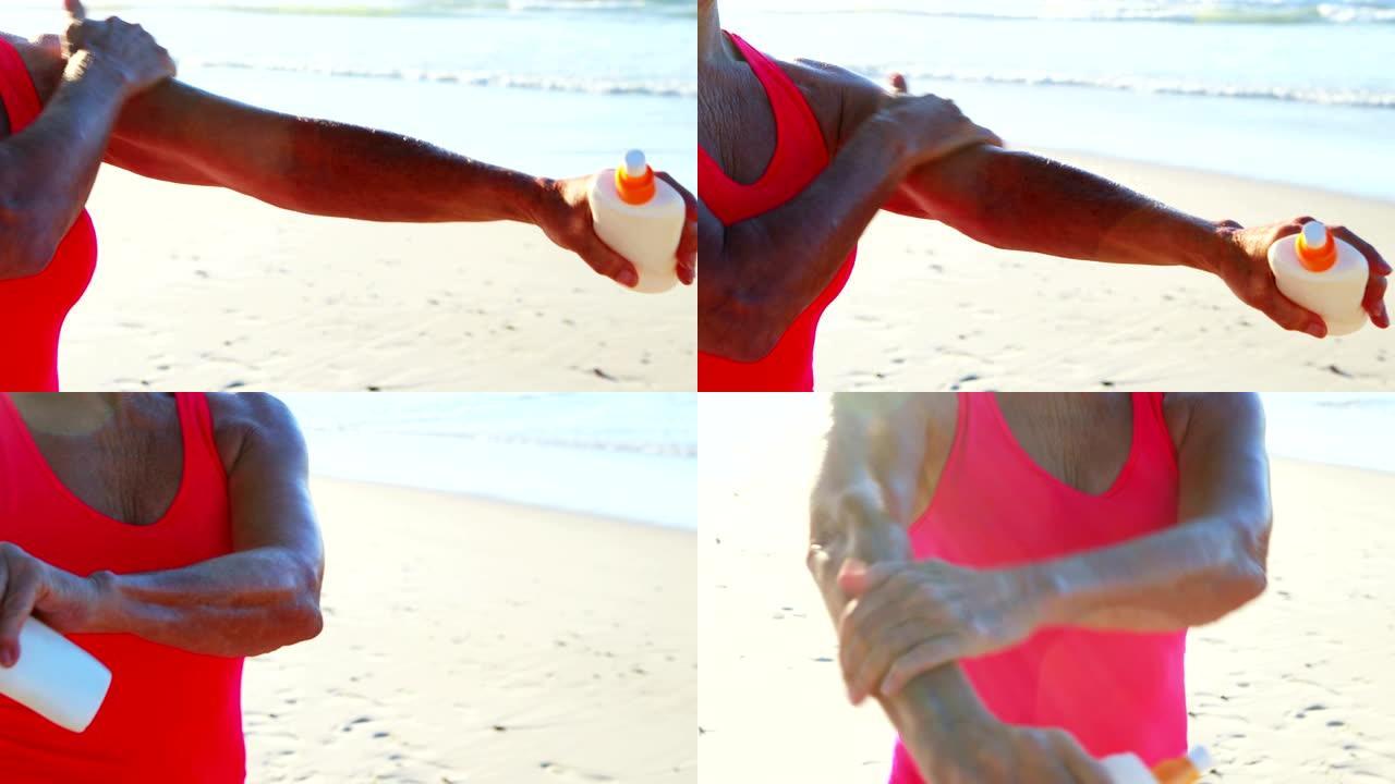 高级妇女在海滩上使用防晒霜