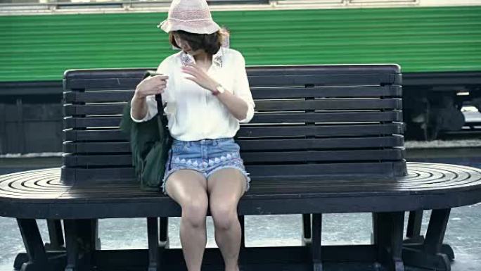 快乐的亚洲女人在夏天在火车站等火车旅行。泰国旅游概念。