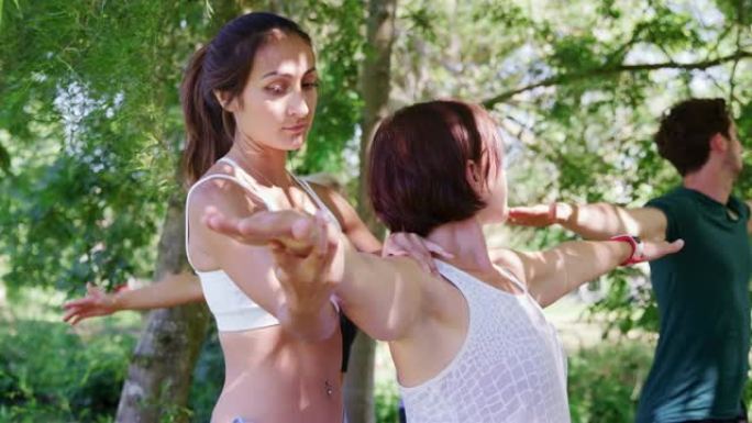 女教练在户外瑜伽课上帮助学生