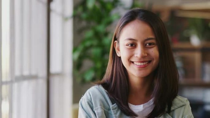 千禧一代亚洲女性创意站在办公室转身对着镜头微笑，特写镜头