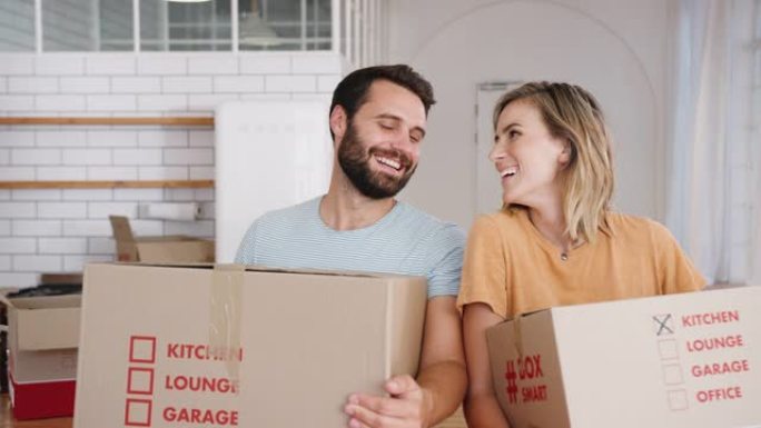 微笑的年轻夫妇在搬家日将箱子搬入新家的肖像