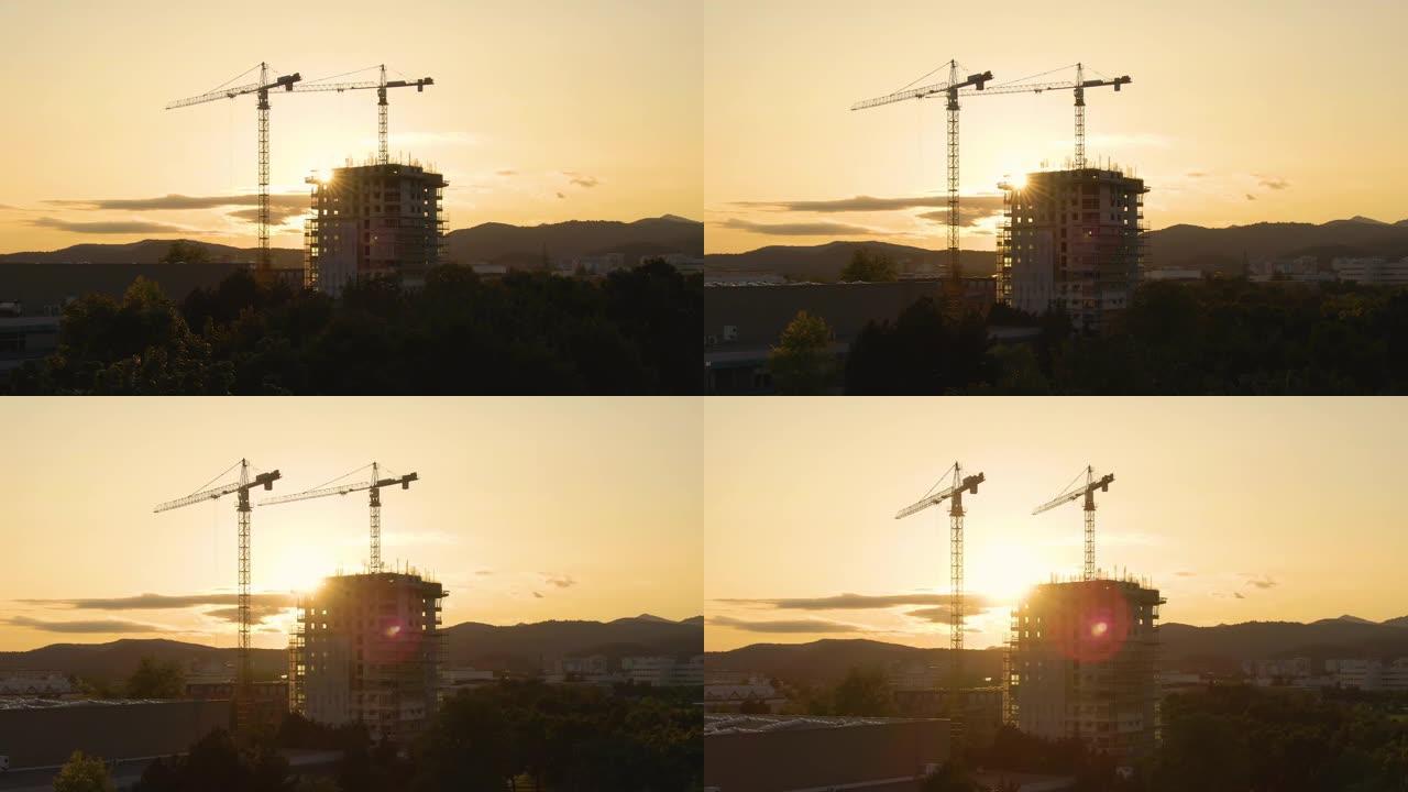 无人机: 金色的日落照亮了绿色小镇上正在建造的摩天大楼
