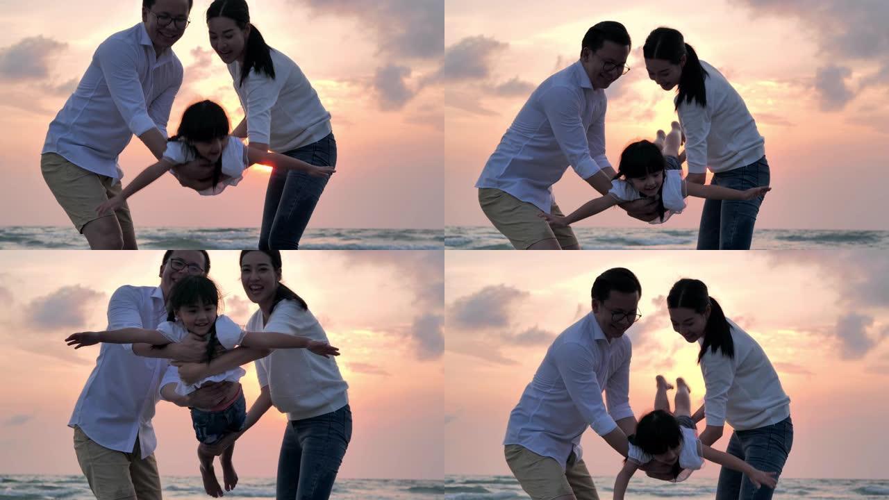 剪影快乐的父亲、母亲、女儿在沙滩上沿着日落海浪的边缘玩得开心。积极的父母和人们在暑假与孩子一起户外活
