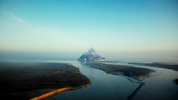 在史诗般的日出高潮，法国标志性的岛屿要塞地标城堡，无人机飞向雾蒙圣米歇尔山